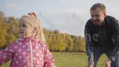 微笑的白种人胡须男教他的小女儿玩肥皂泡。 可爱的金发女孩穿着点缀的粉红色